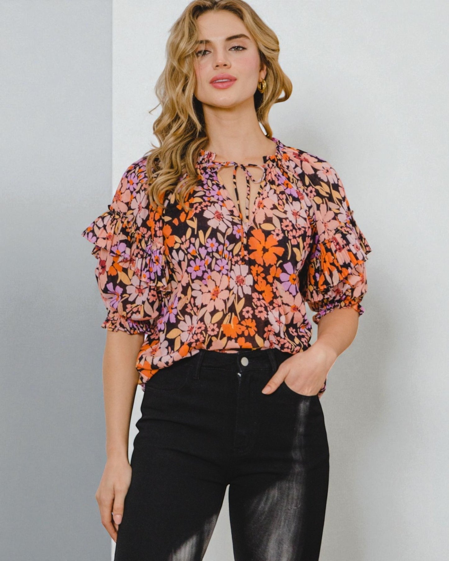 Woman wearing a floral blouse with puff sleeves against a plain background