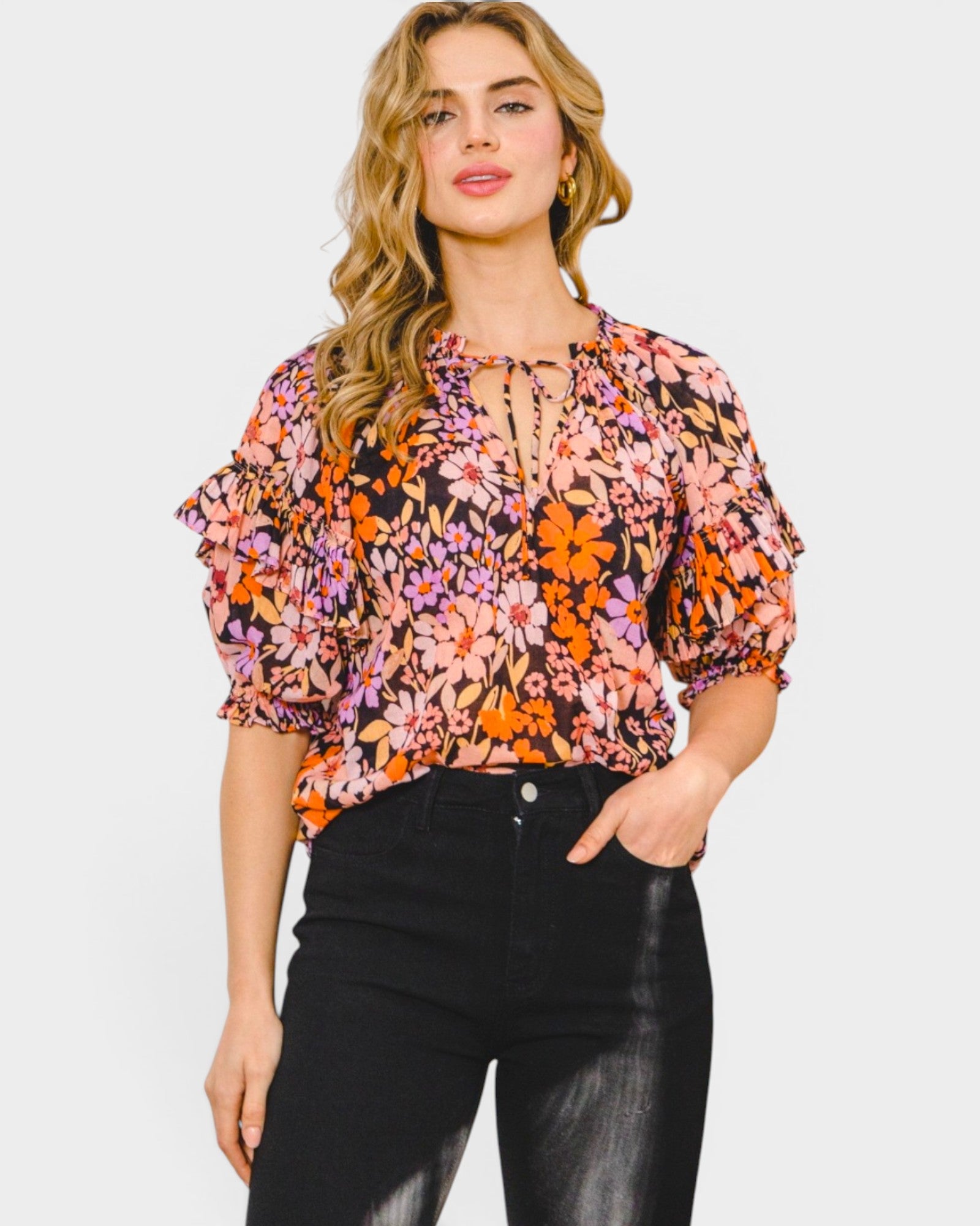 Woman wearing a floral blouse with black pants on a white background
