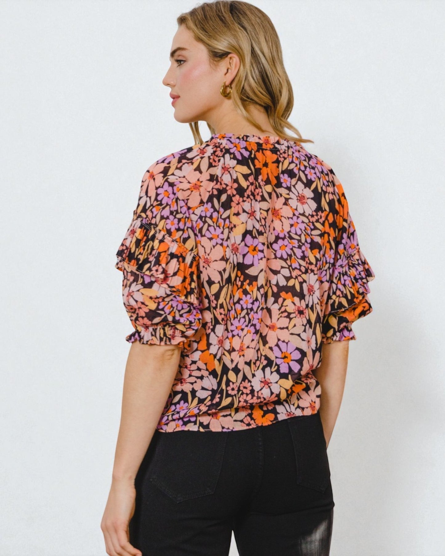 Woman wearing a colorful floral blouse against a white background