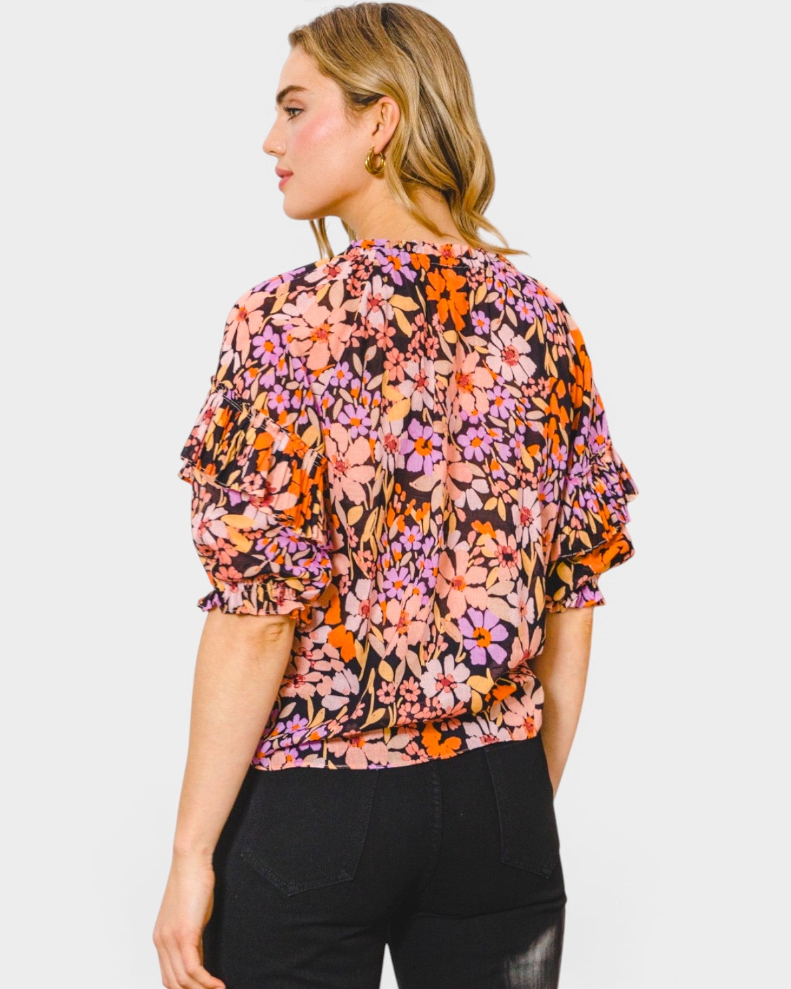 Woman wearing a colorful floral blouse against a white background