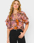 Woman wearing a colorful floral blouse against a plain background
