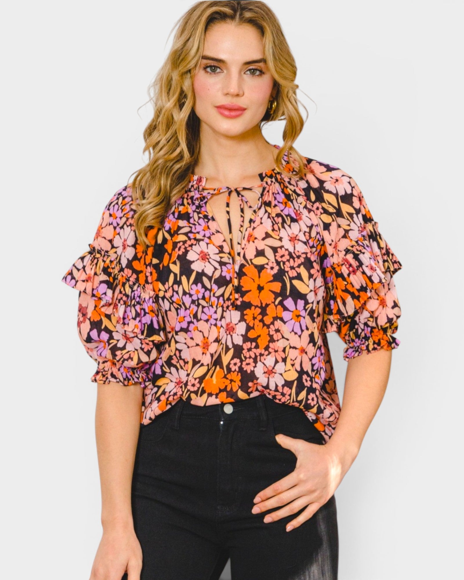 Woman wearing a floral blouse with puff sleeves on a plain background