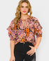 Woman wearing a floral blouse with puff sleeves on a plain background