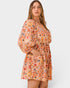 Woman wearing a patterned orange romper on a white background