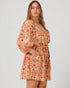 Woman wearing a patterned dress on a plain background