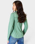 Woman wearing a green long-sleeve shirt and blue jeans on a white background