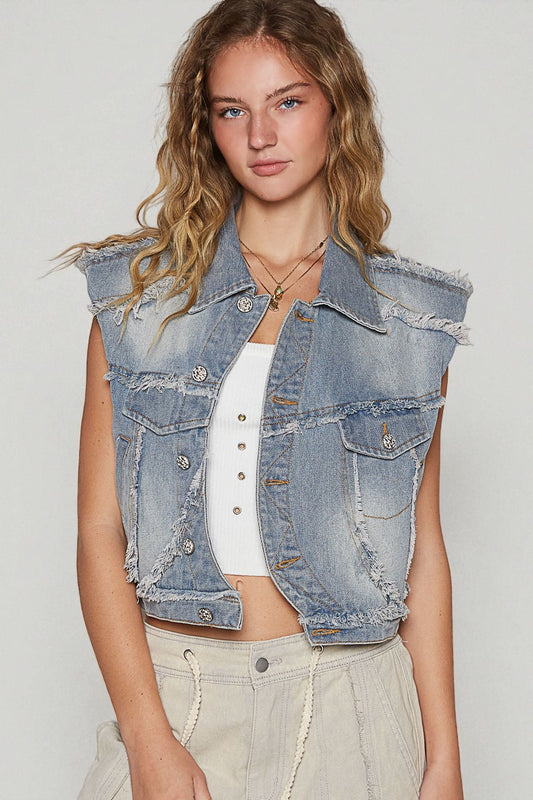 Woman wearing a denim vest over a white top on a plain background