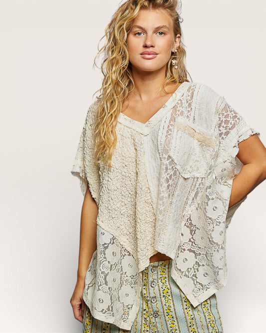 Woman wearing a lace top and patterned pants on a plain background