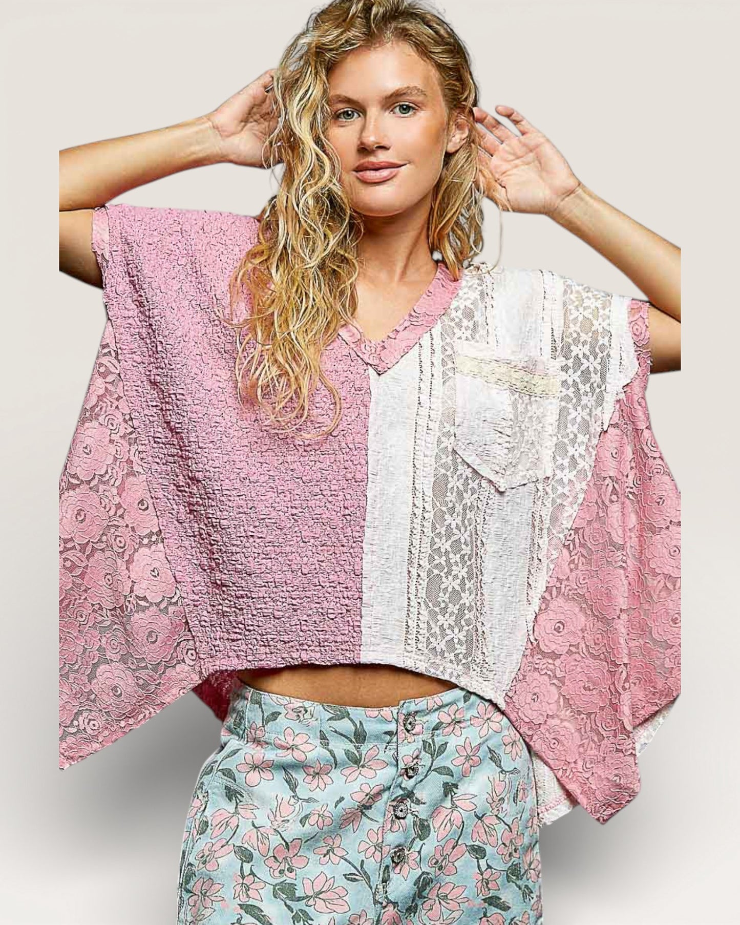 Woman wearing a pink and white patterned top with floral pants on a light background