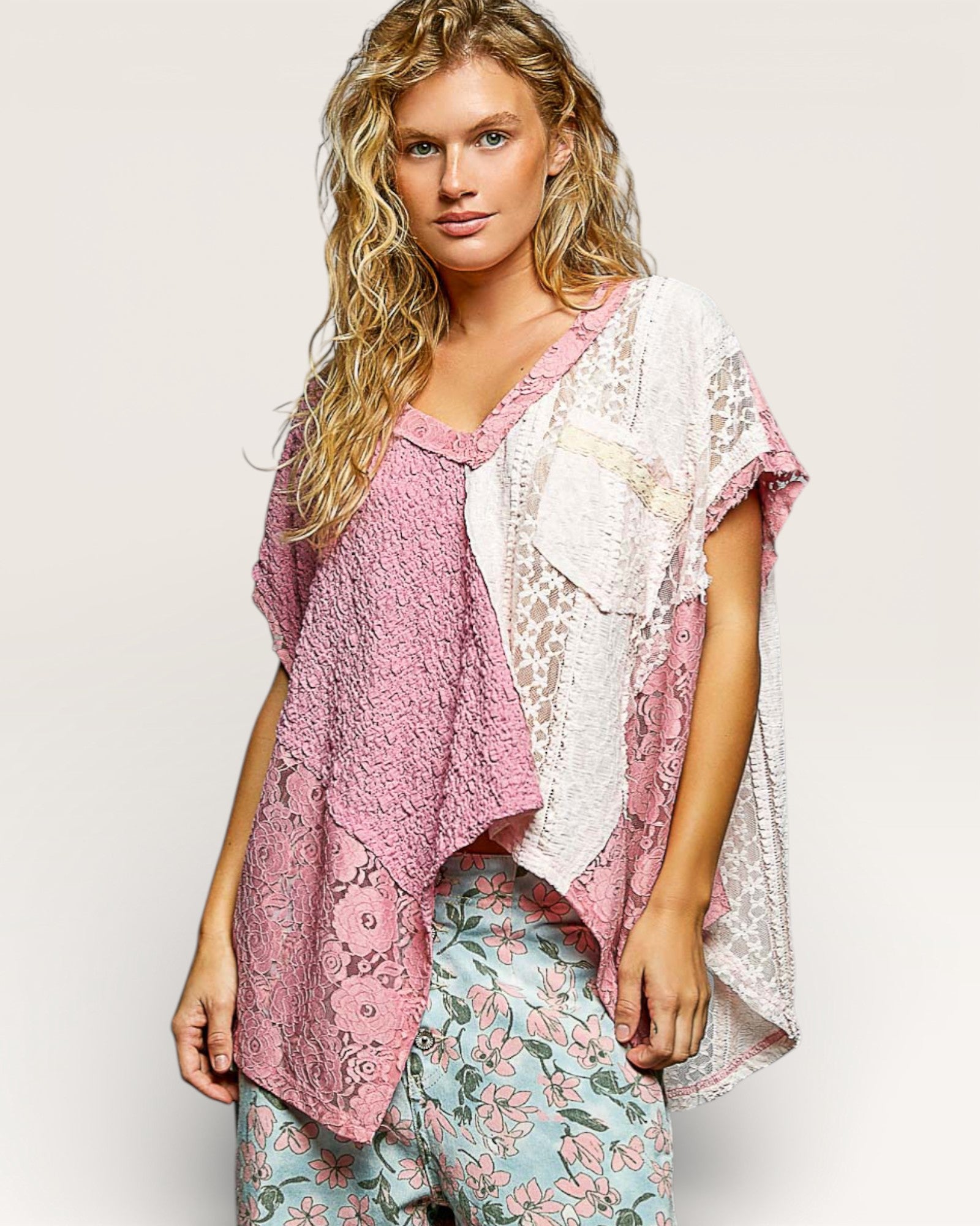 Woman wearing a pink lace top and floral pants on a plain background