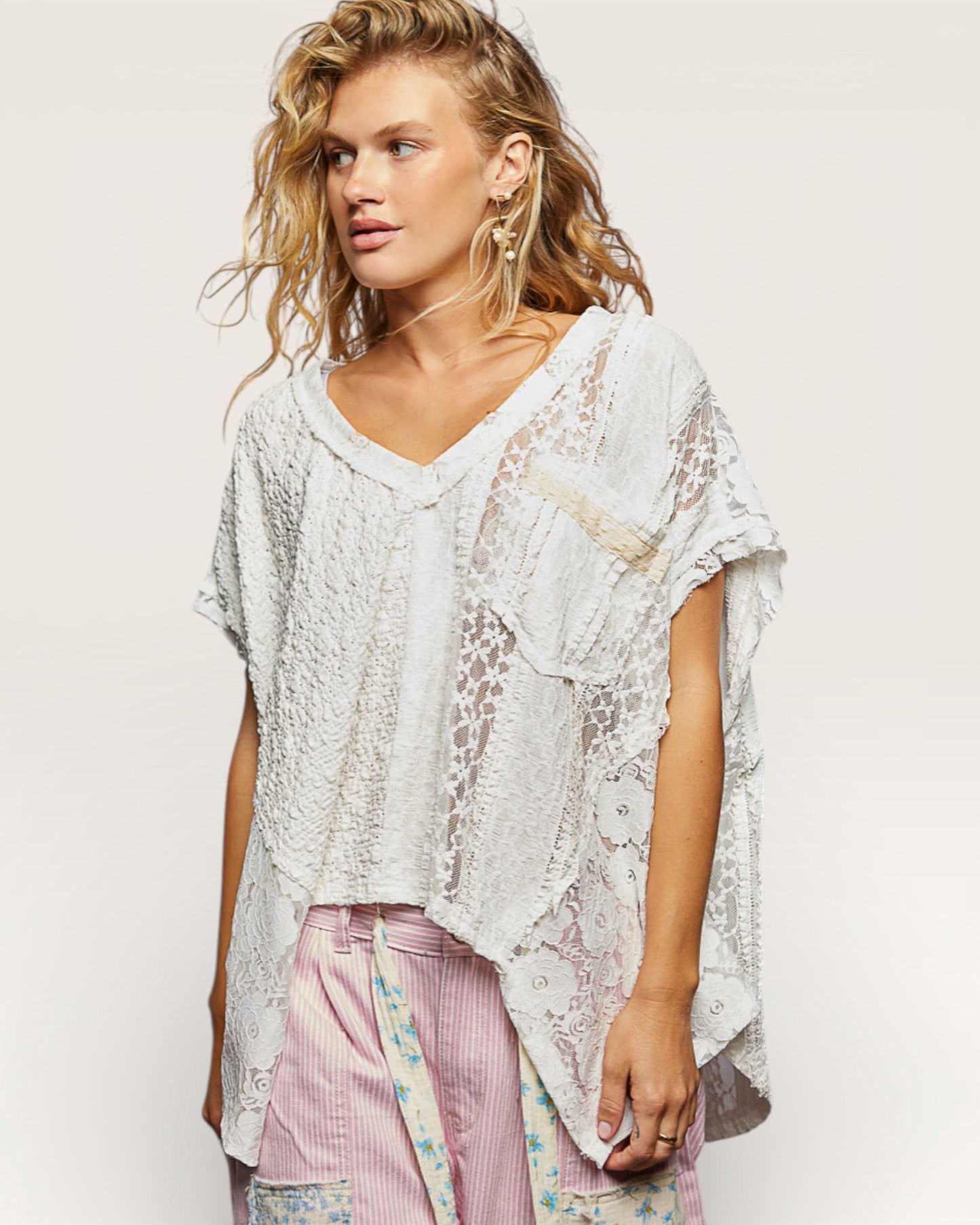 Woman wearing a white lace top with a plain background