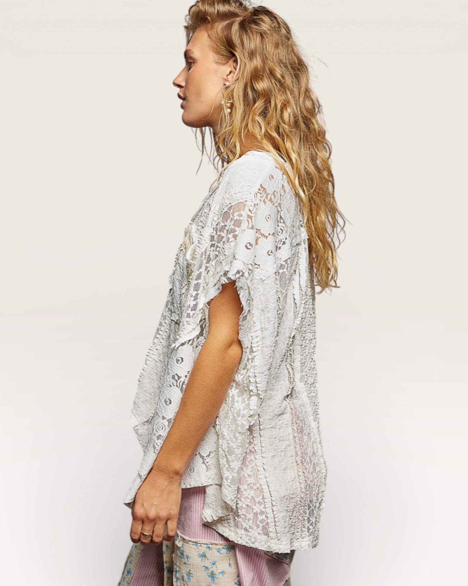 Woman wearing a light-colored lace top against a plain background