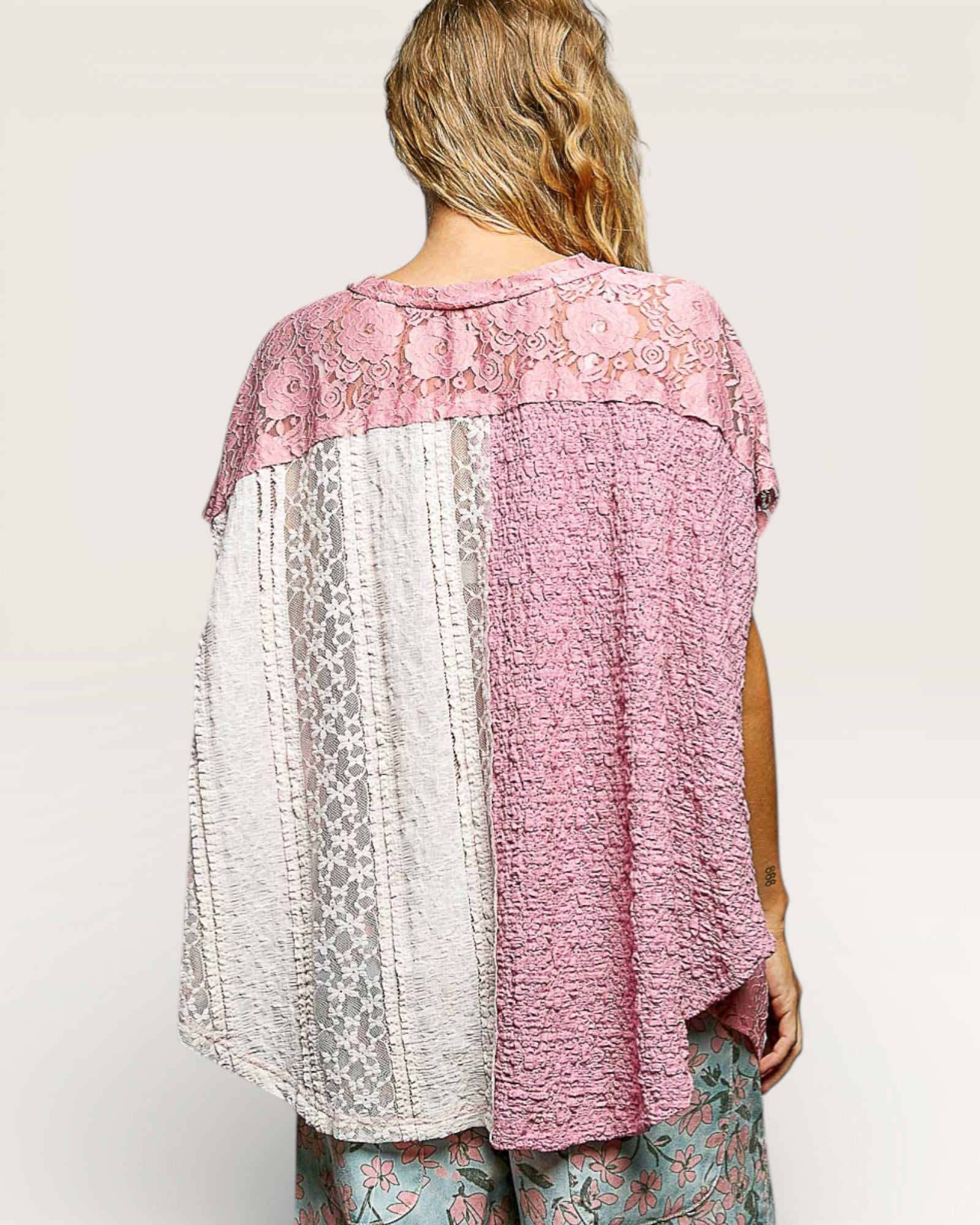 Woman wearing a pink and white patterned top with a plain background