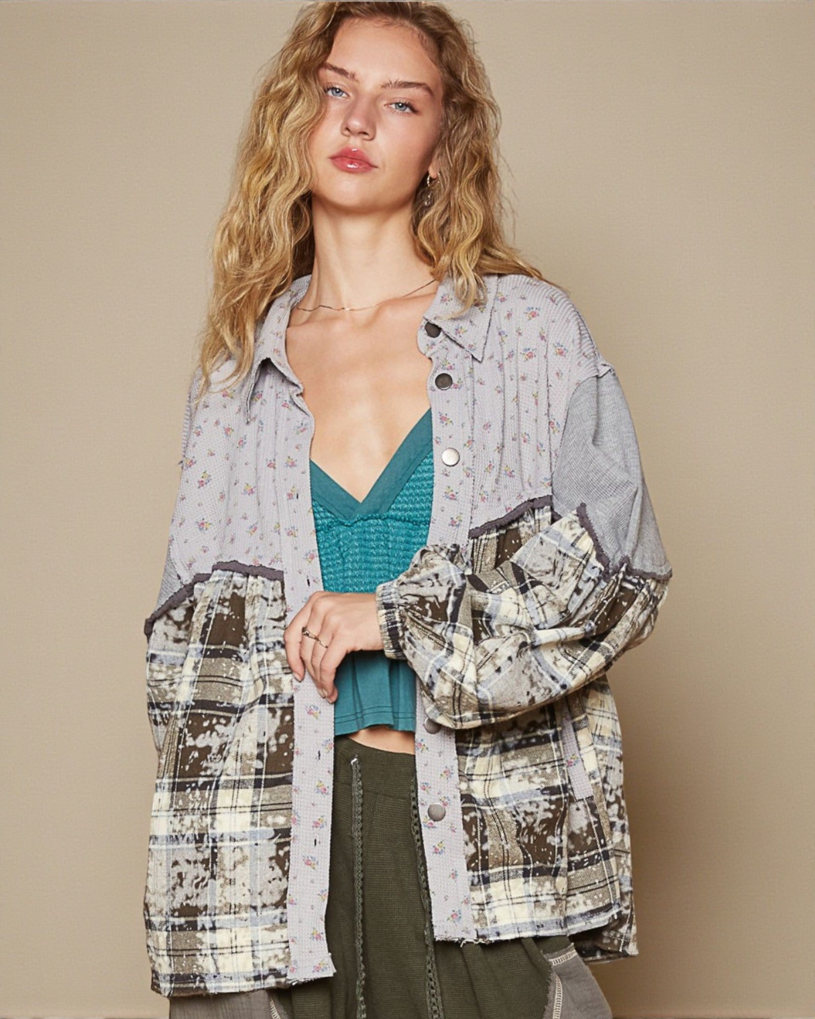 Woman wearing a patterned shirt over a teal top with a beige background