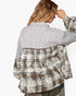A woman shown from the back wearing a patchwork button-up shirt with a light floral yoke, gray sleeves, and a distressed brown plaid lower section, against a plain white background.