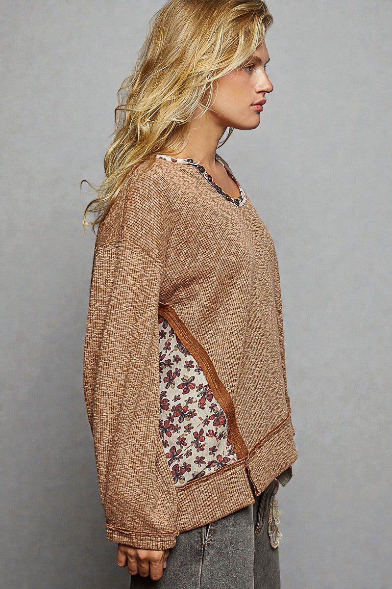 Woman wearing a brown sweater with floral pattern on a gray background