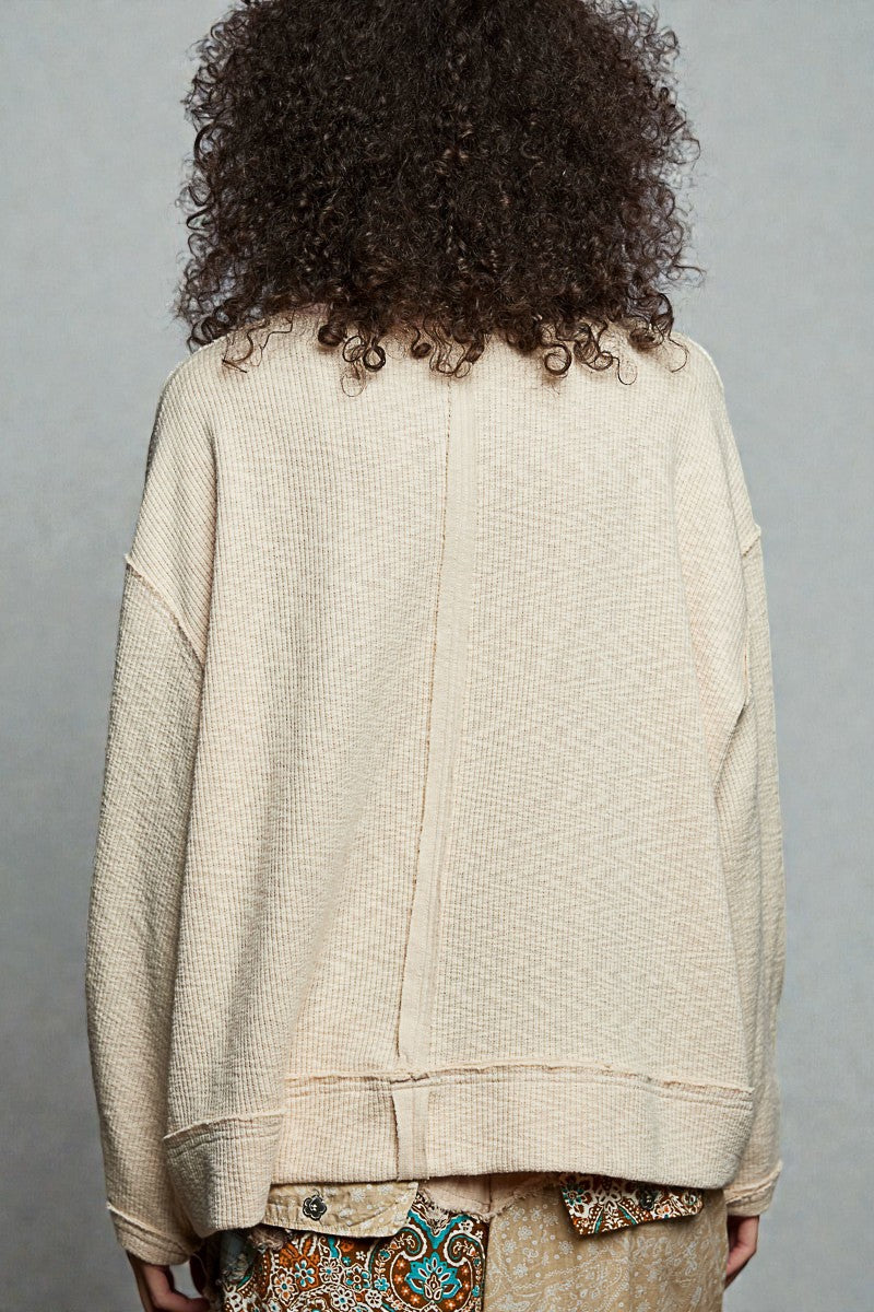 Person wearing a beige textured jacket with a gray background