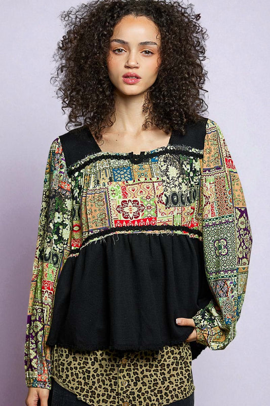 Woman wearing a colorful patchwork top with a black base on a light gray background