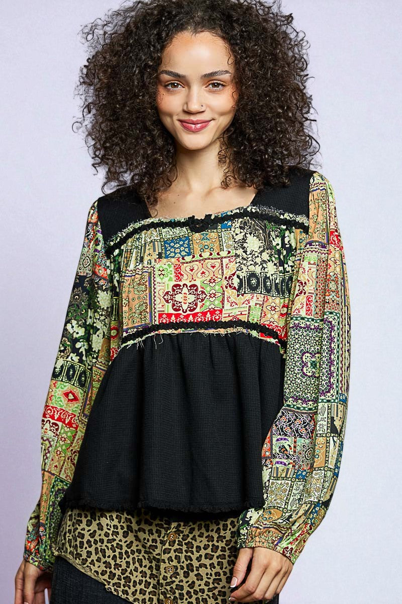 Woman wearing a colorful patchwork top with a black base on a plain background