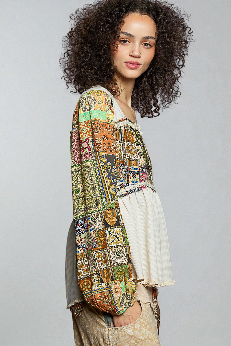 Woman wearing a colorful patterned top with a plain background