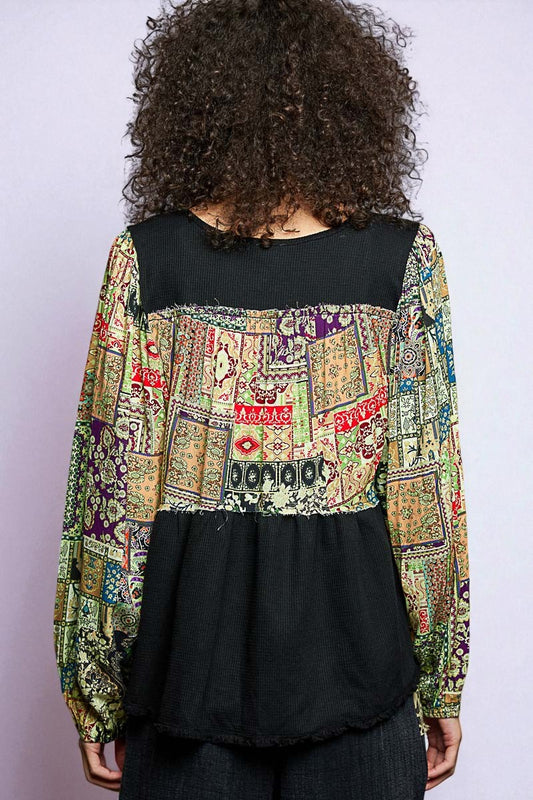 Person wearing a colorful patterned top with a black base on a plain background