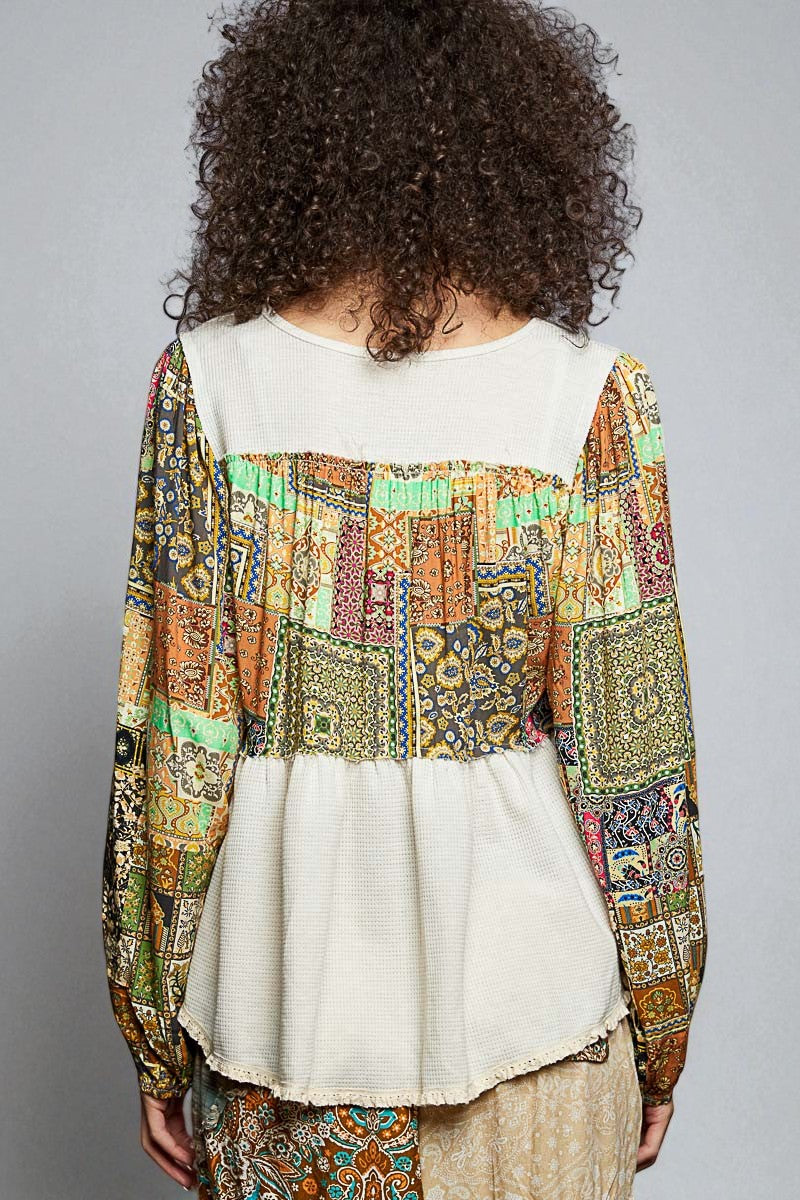 Person wearing a colorful patterned top over a white shirt on a gray background