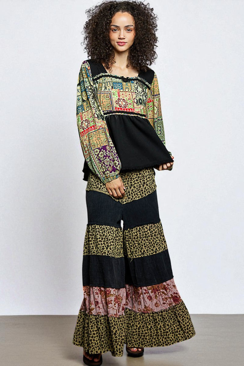 Woman wearing a colorful patterned top and wide-leg pants on a white background