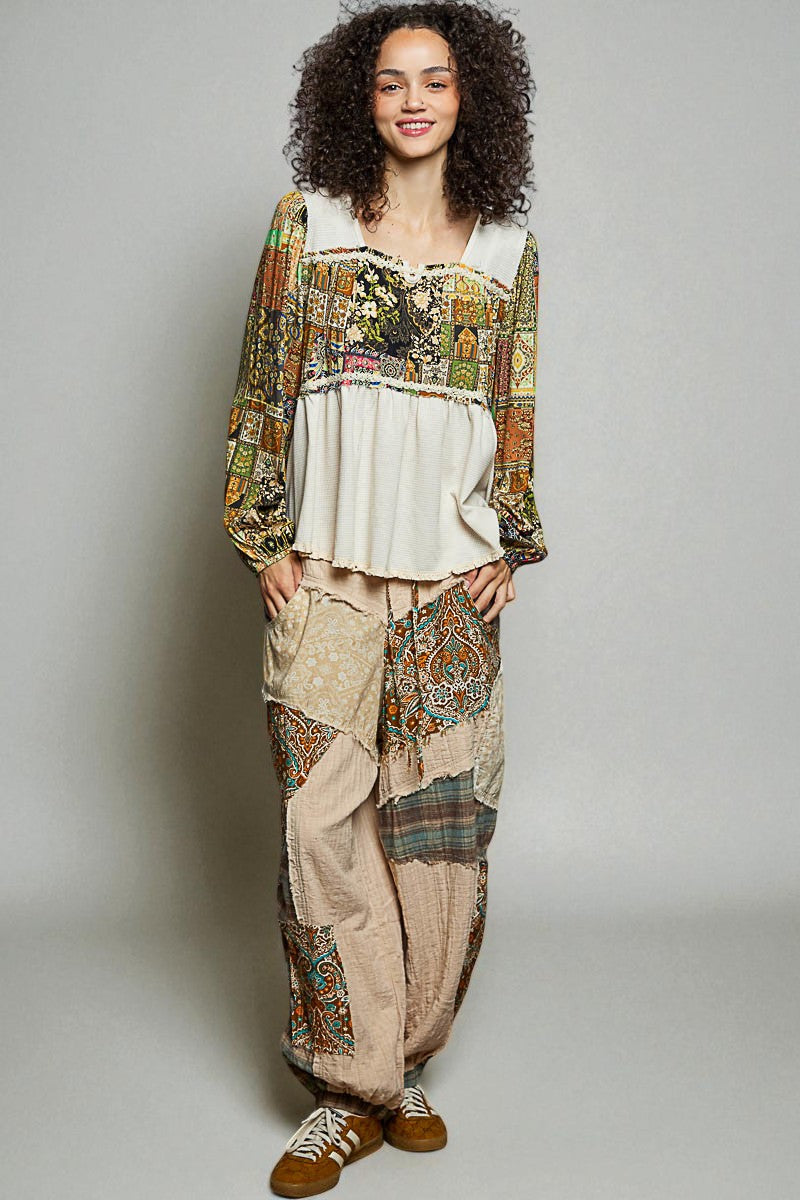 Woman wearing a bohemian outfit with patterned top and pants on a plain background