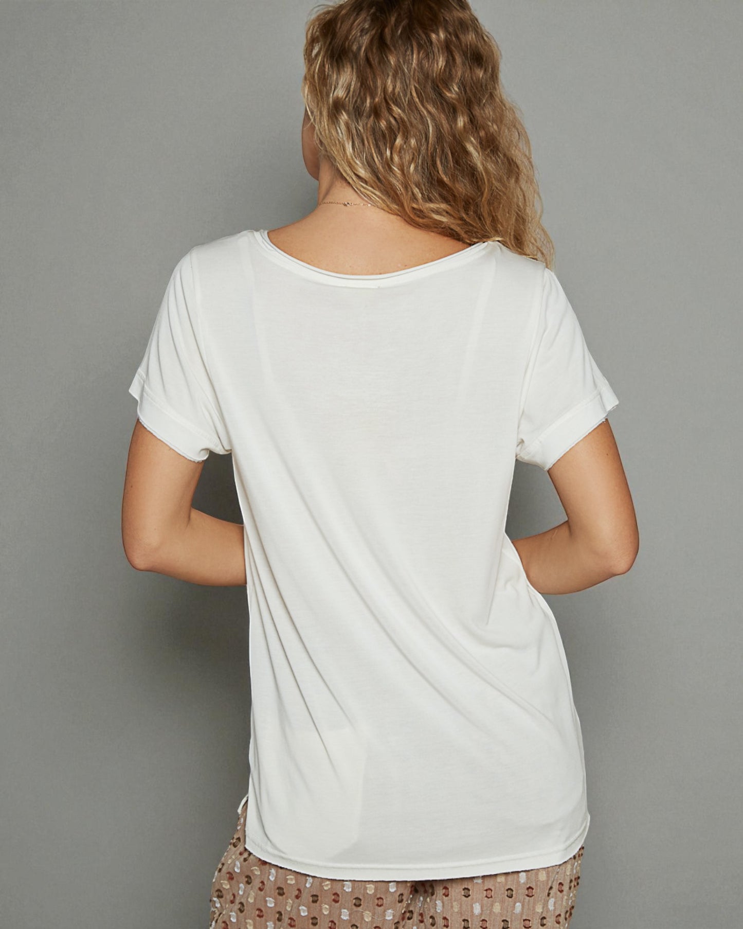 Person wearing a plain white t-shirt against a gray background