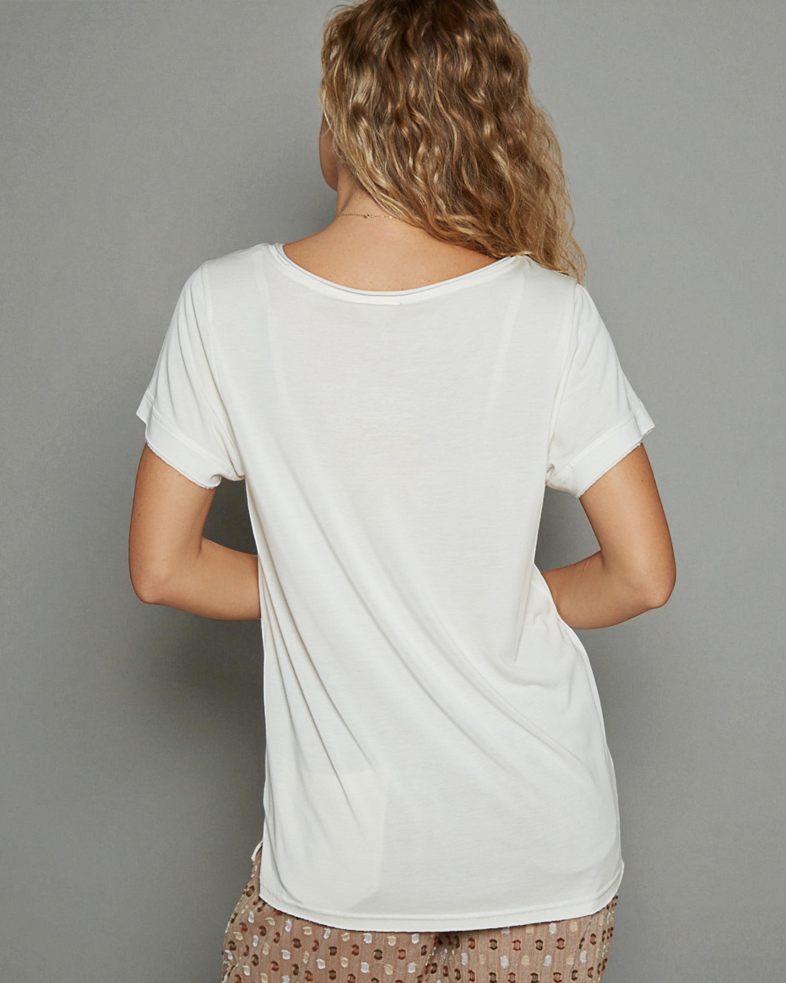 Person wearing a plain white t-shirt against a gray background