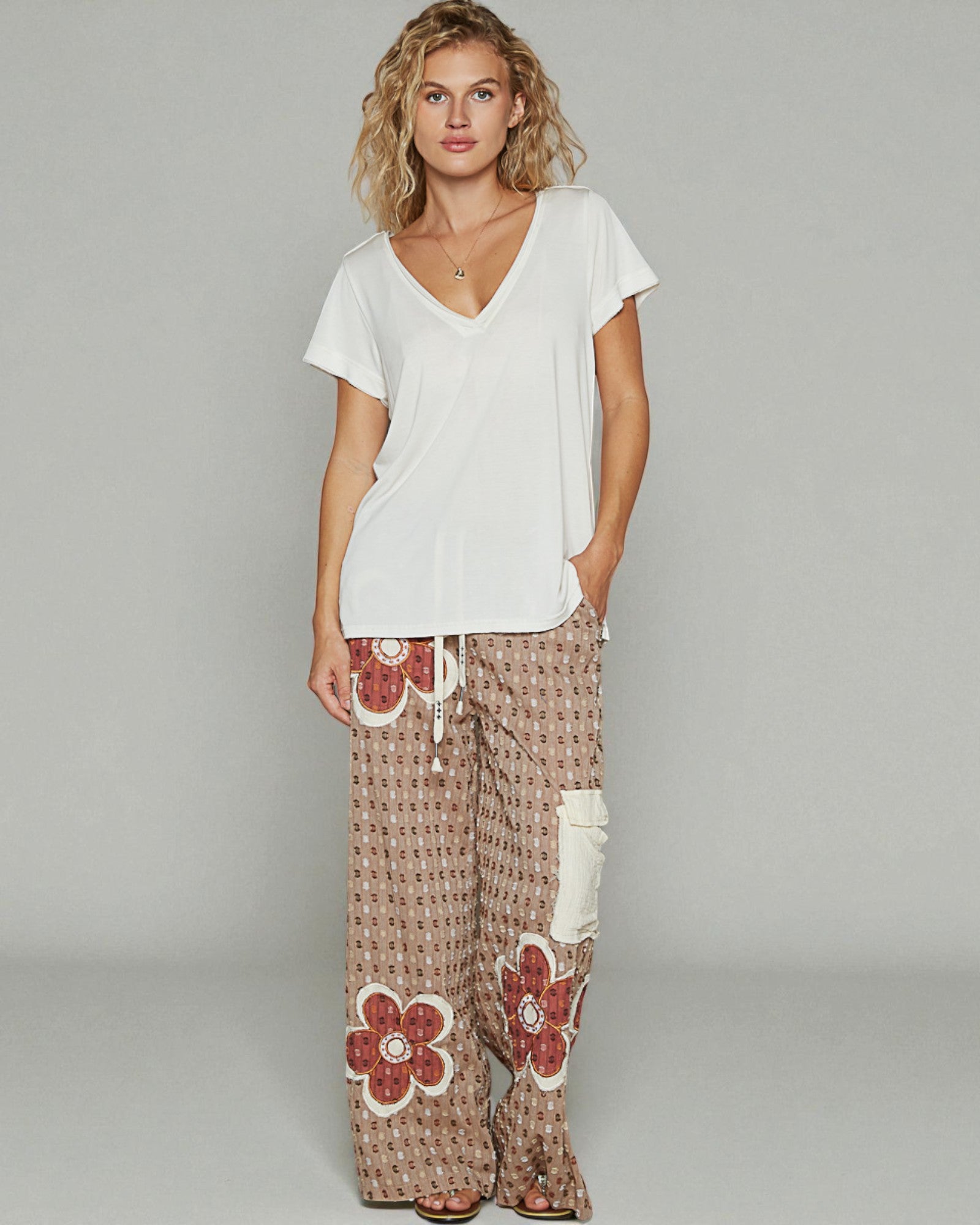 Woman wearing a white top and patterned pants on a gray background