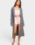 Woman wearing a gray cardigan, pink and white striped top, and shorts on a white background