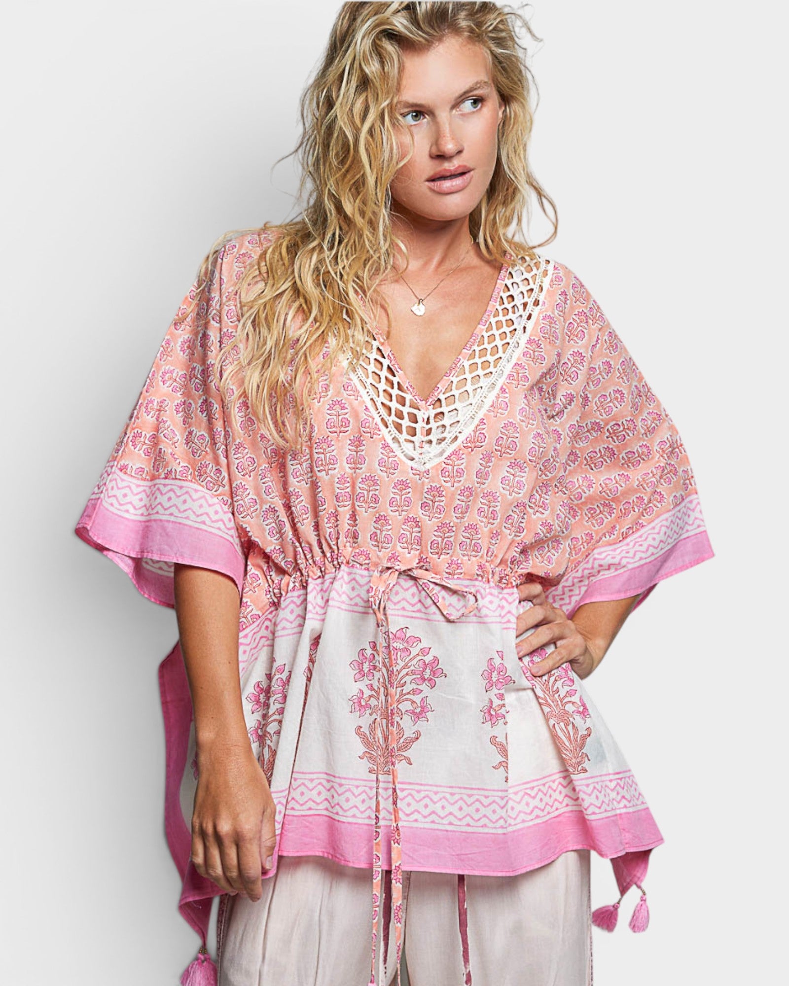 Woman wearing a pink and white patterned top on a plain background