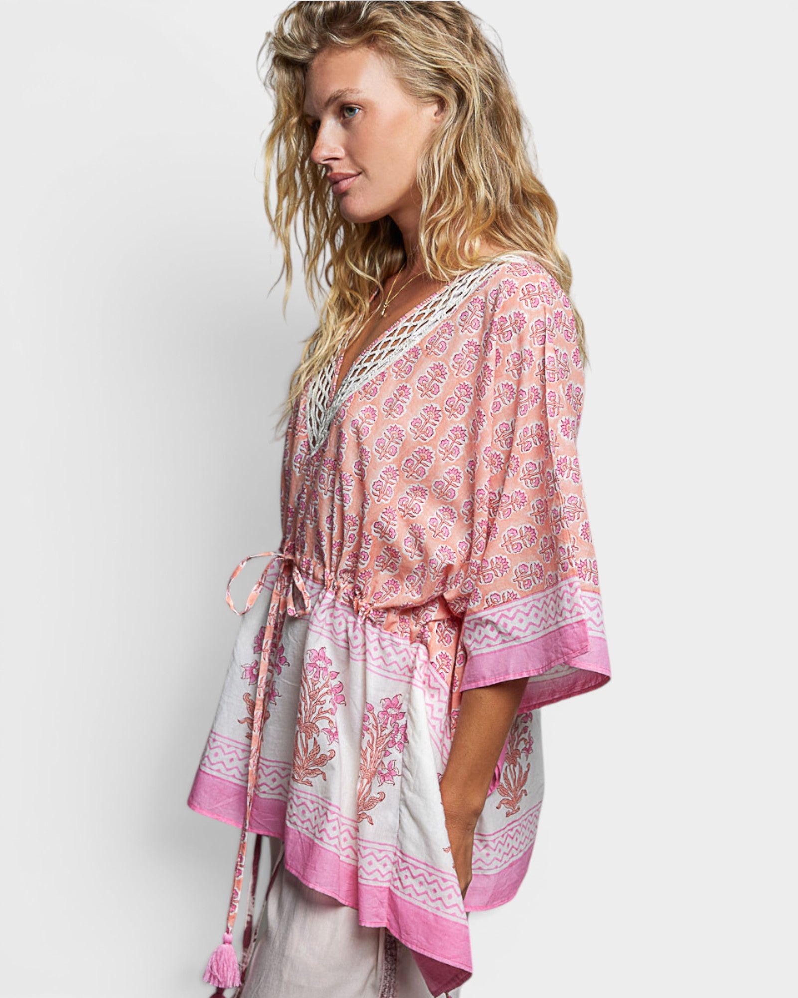 Woman wearing a pink and white patterned kimono-style top on a light gray background