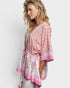 Woman wearing a pink and white patterned kimono-style top on a light gray background