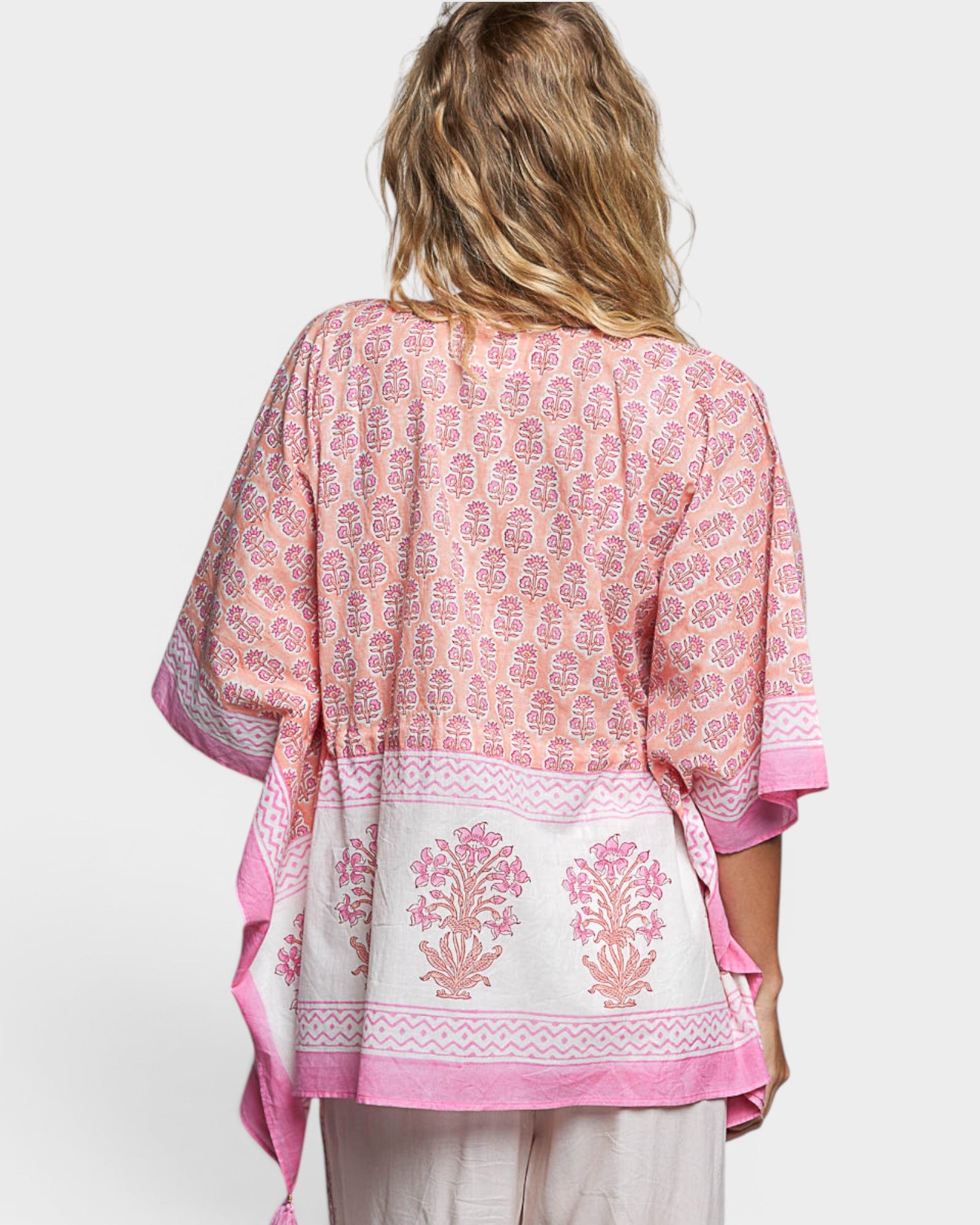 Woman wearing a pink and white patterned outfit on a white background