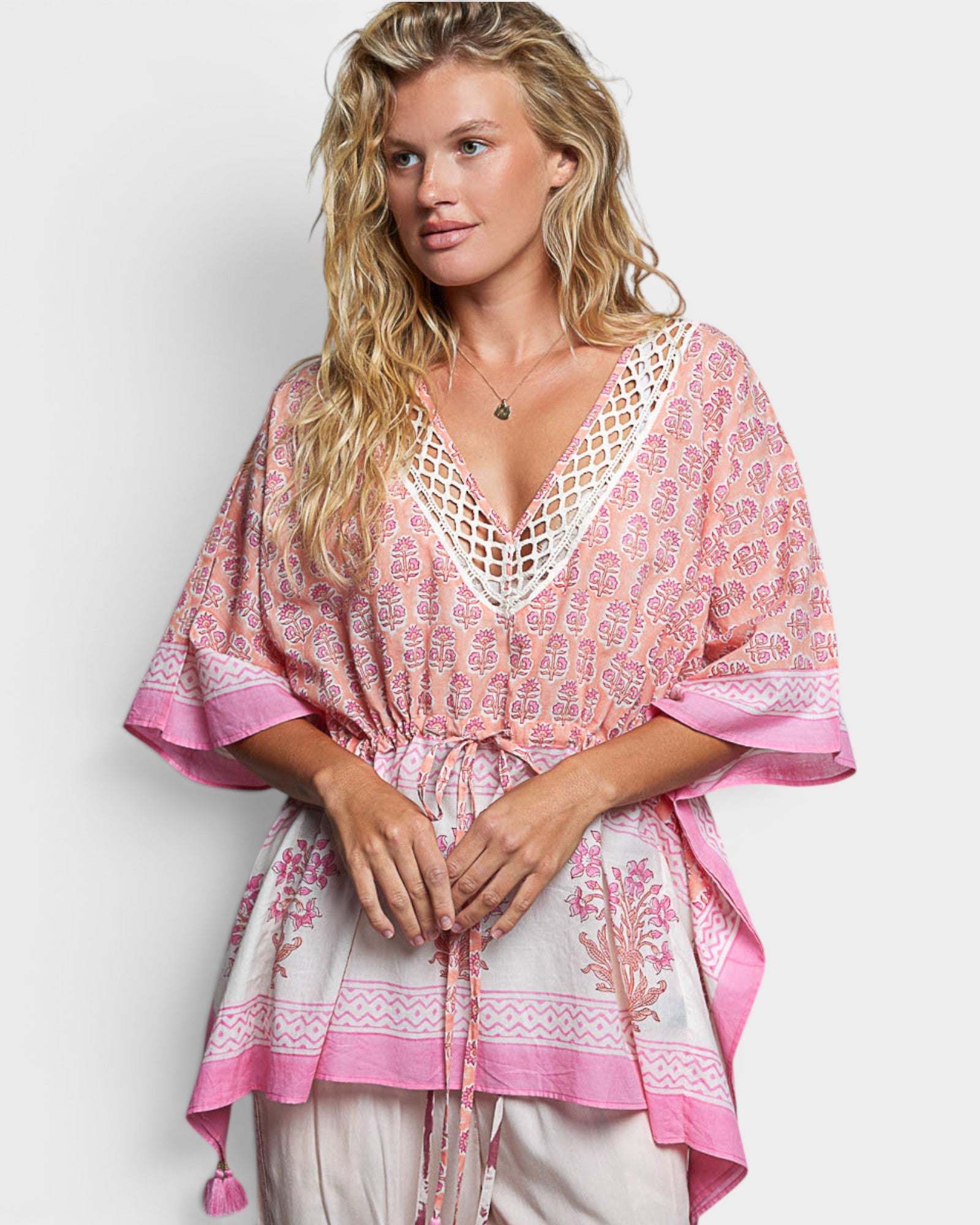 Woman wearing a pink and white patterned top on a plain background