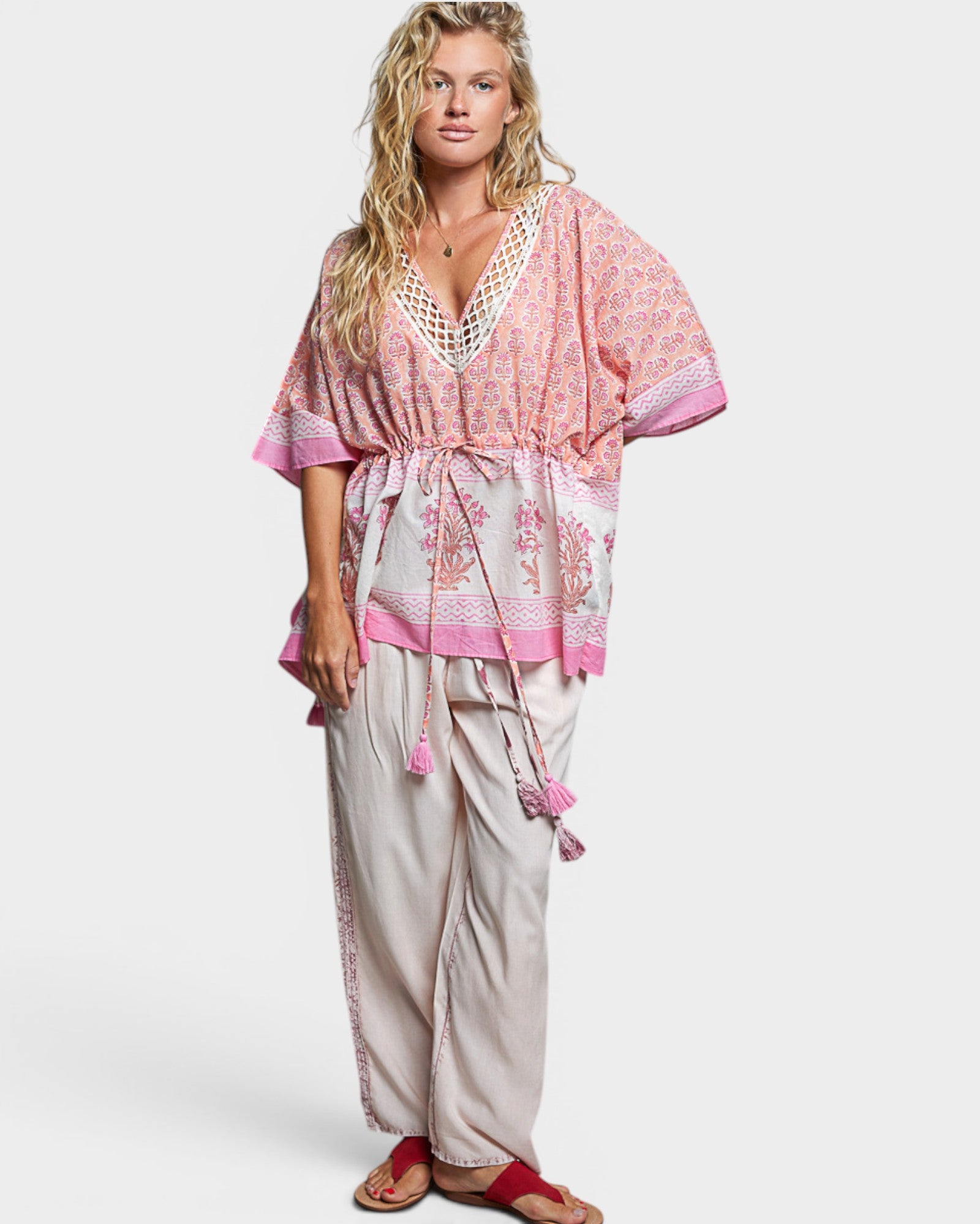 Woman wearing a pink and white patterned outfit on a plain background