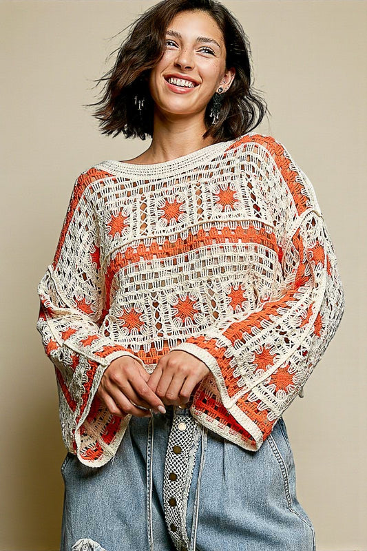 Woman wearing a white lace top with orange accents and blue jeans against a beige background