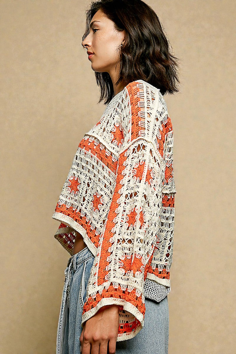 Woman wearing a white and orange crochet poncho against a beige background