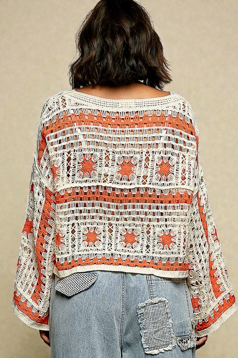 Person wearing a crochet top with orange and red patterns on a beige background