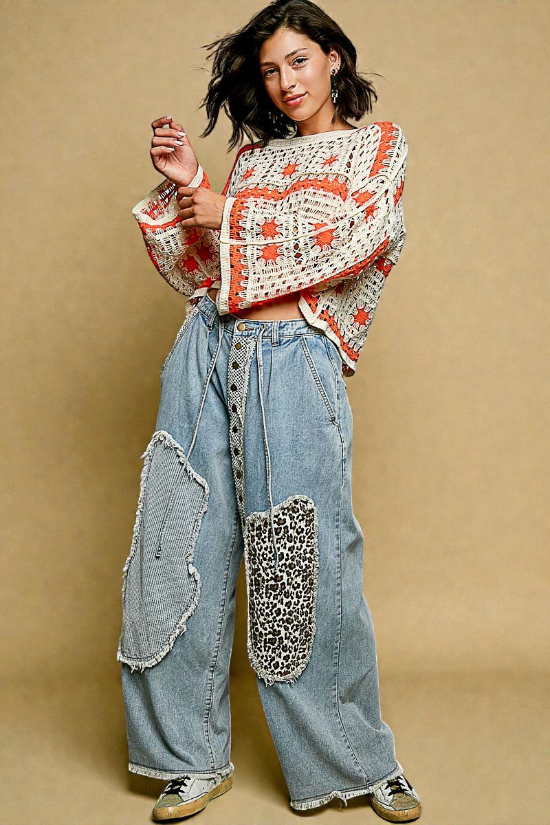 Woman wearing a patterned top and denim pants with leopard print patches on a beige background