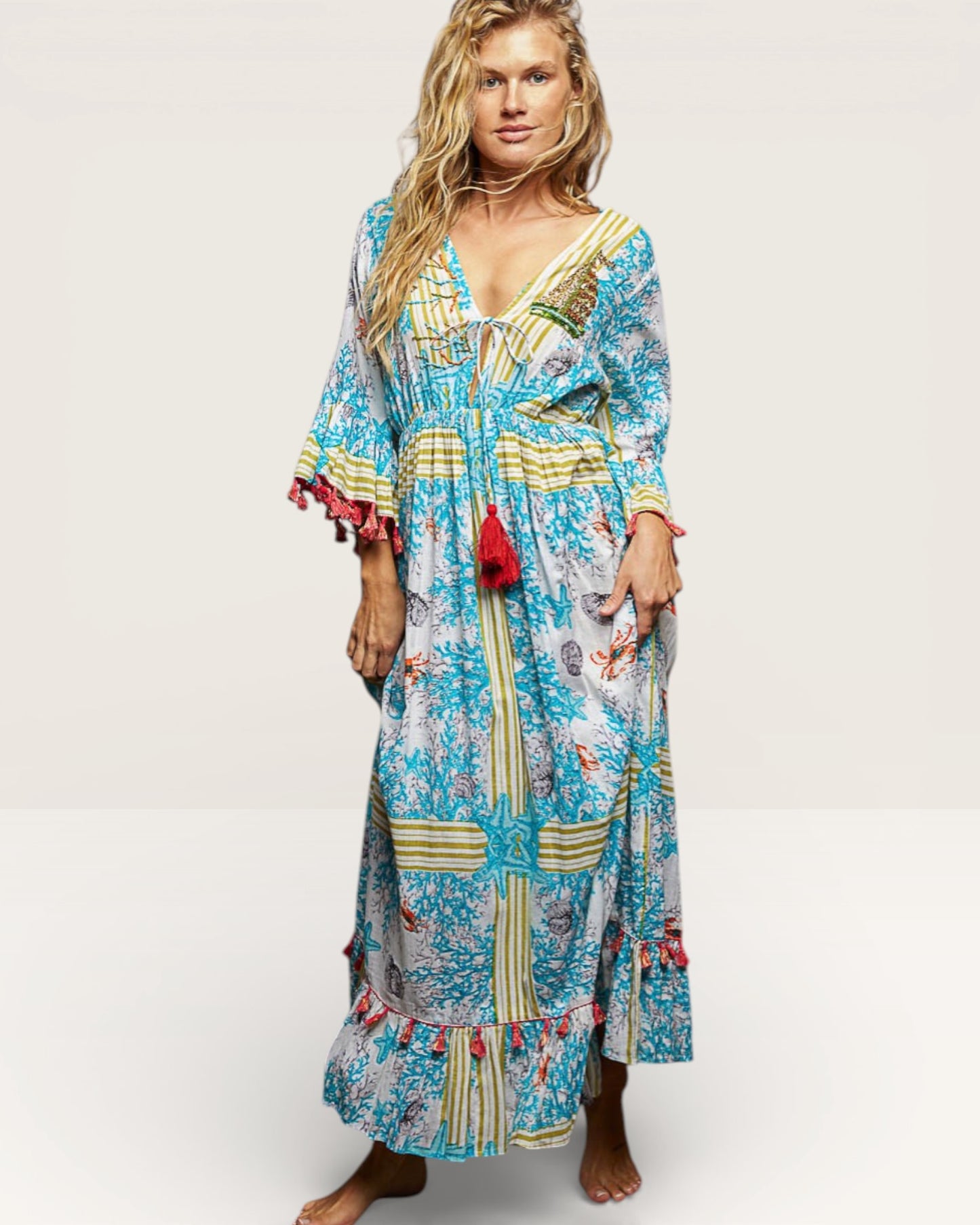 Woman wearing a colorful patterned dress with tassels on a white background