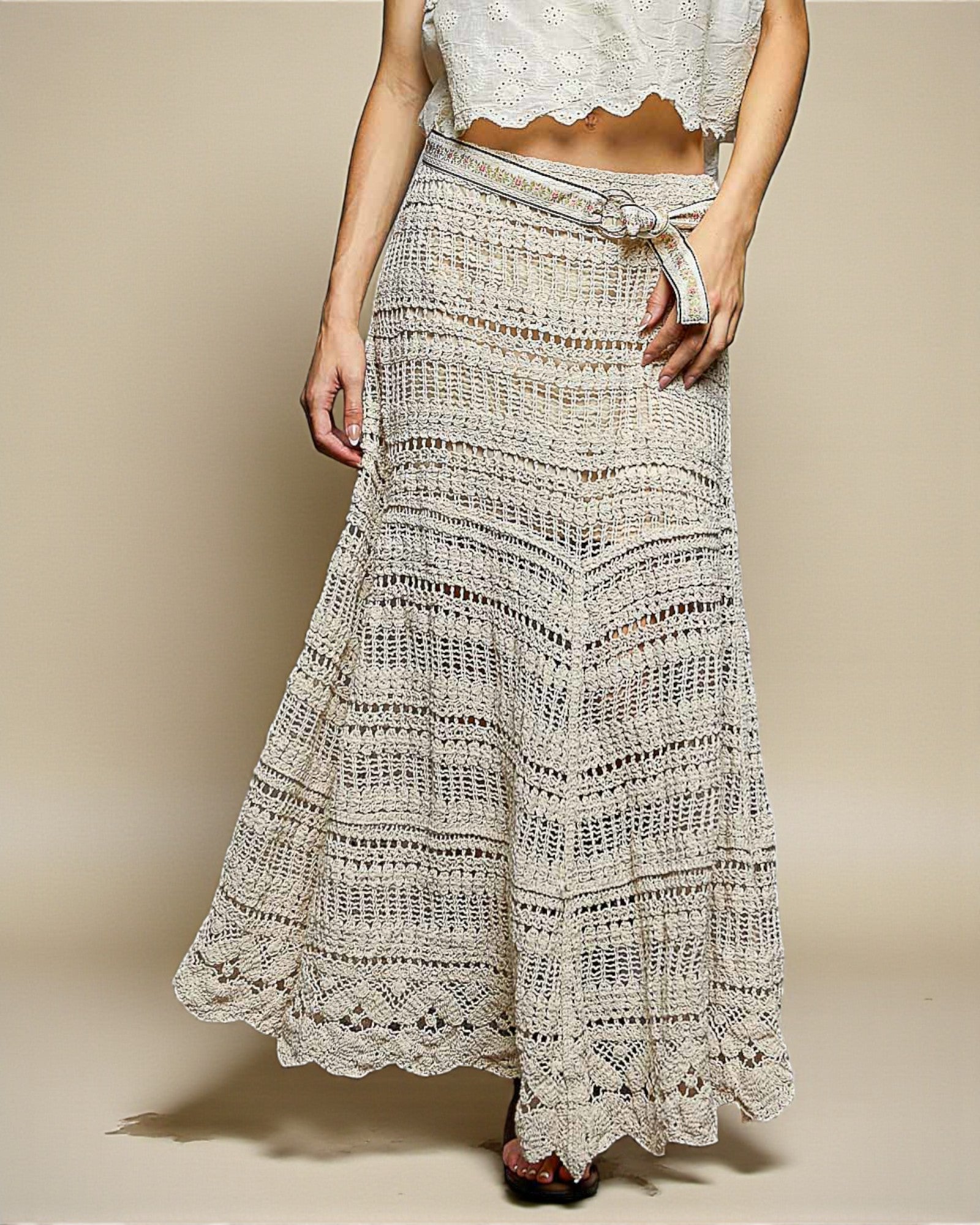Person wearing a long, patterned skirt on a plain background