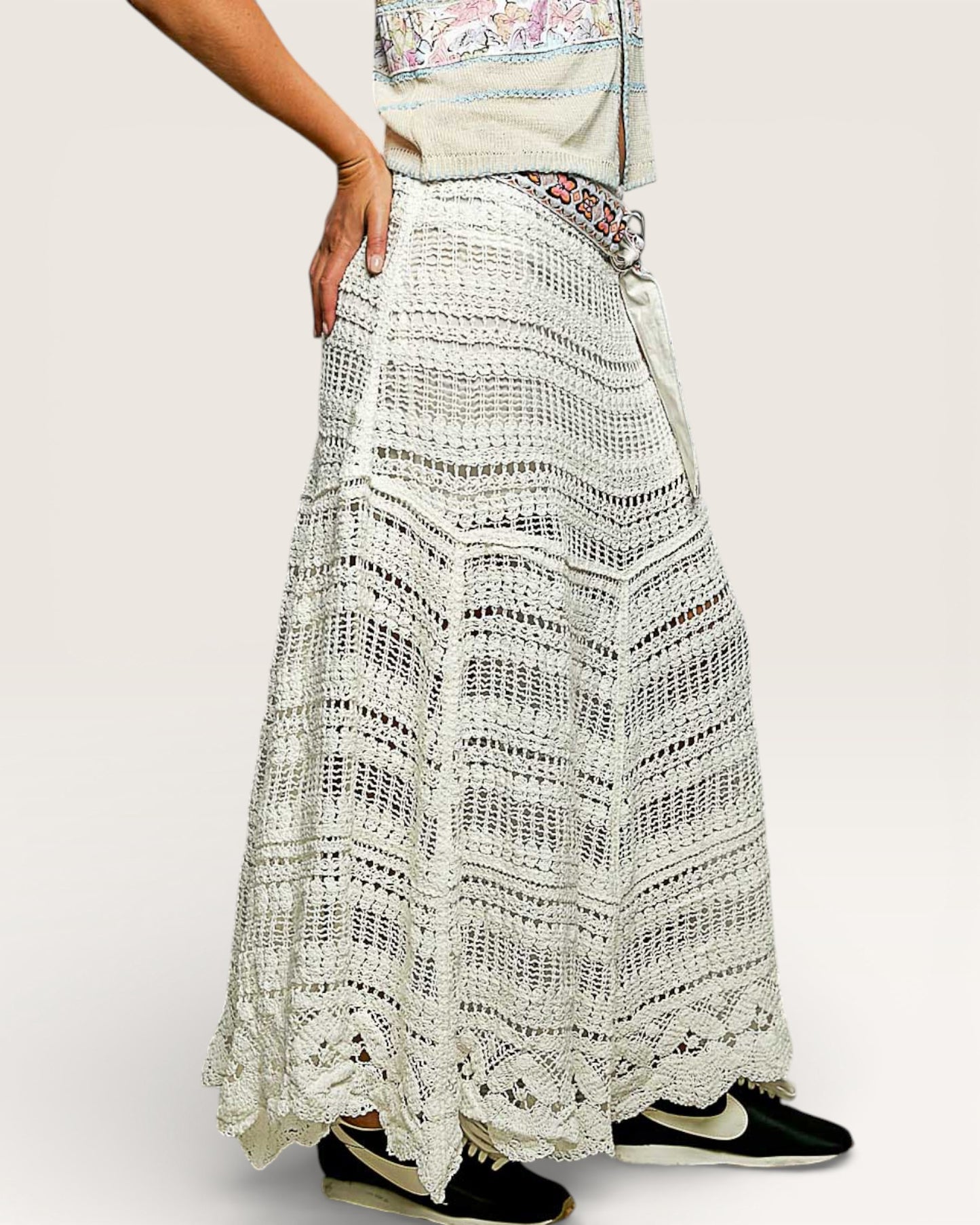 Person wearing a long, patterned skirt with sneakers on a plain background