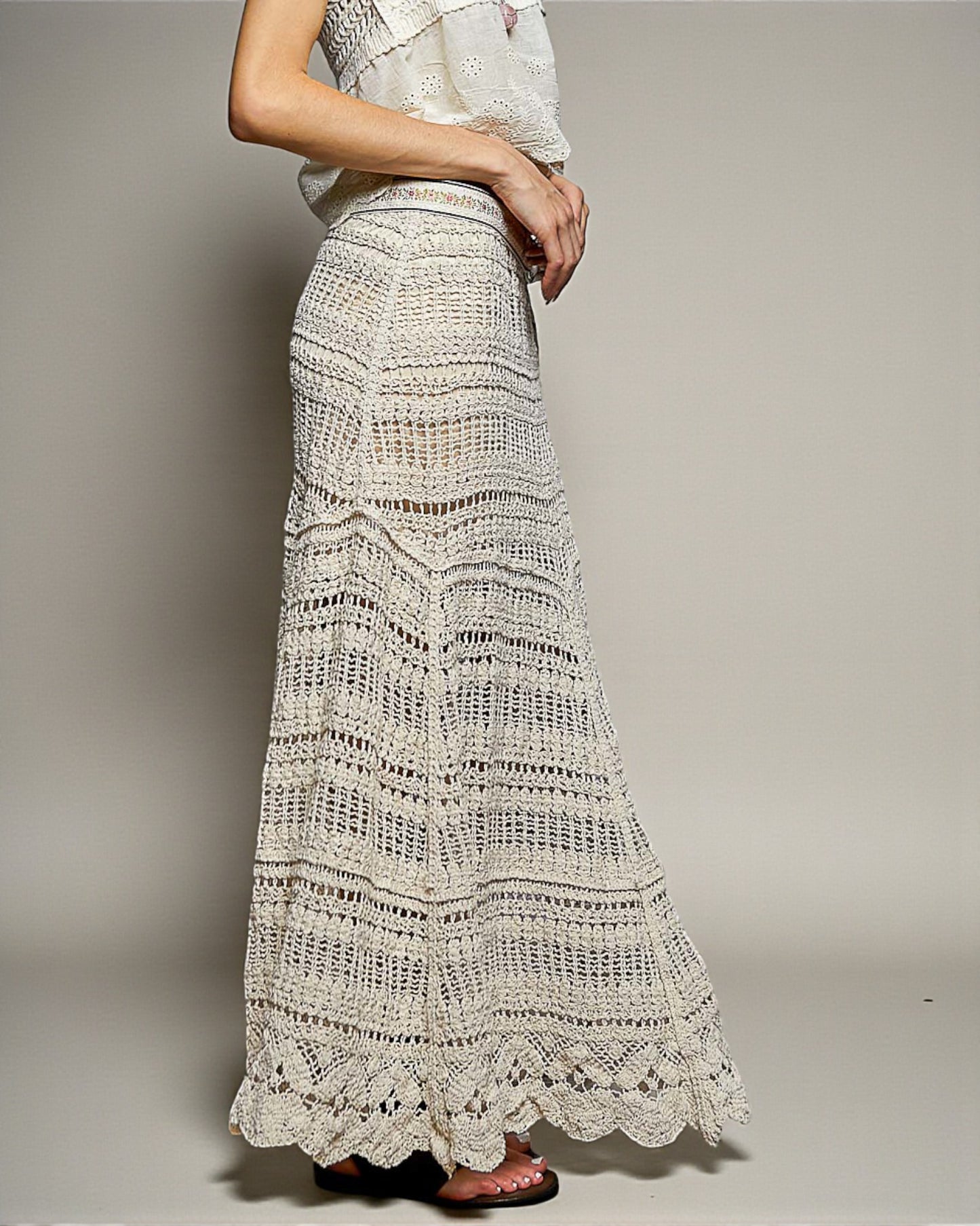 Long white lace skirt worn by a person on a plain background