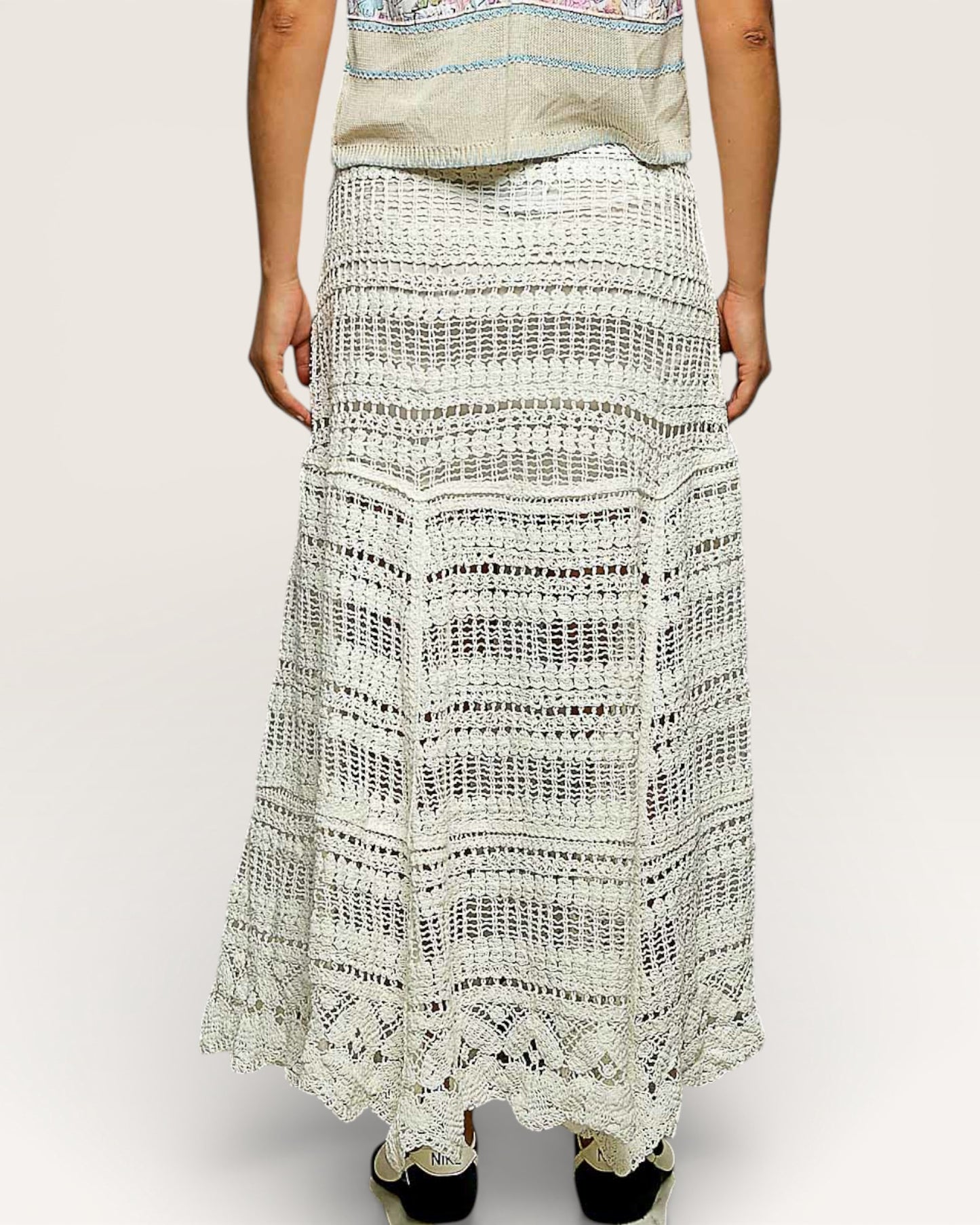 Person wearing a long, patterned skirt on a plain background
