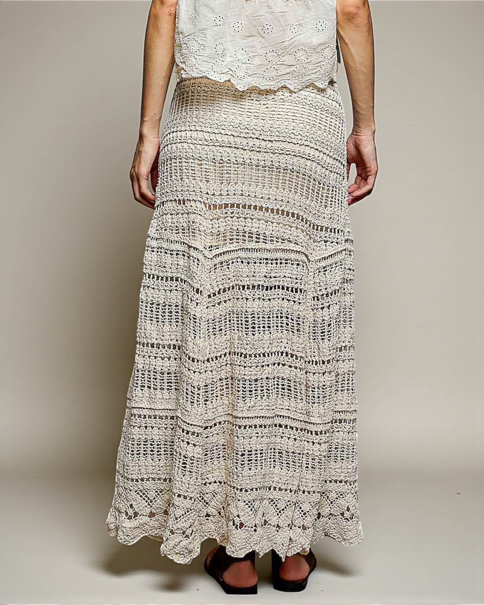 Person wearing a long, patterned skirt with a plain background