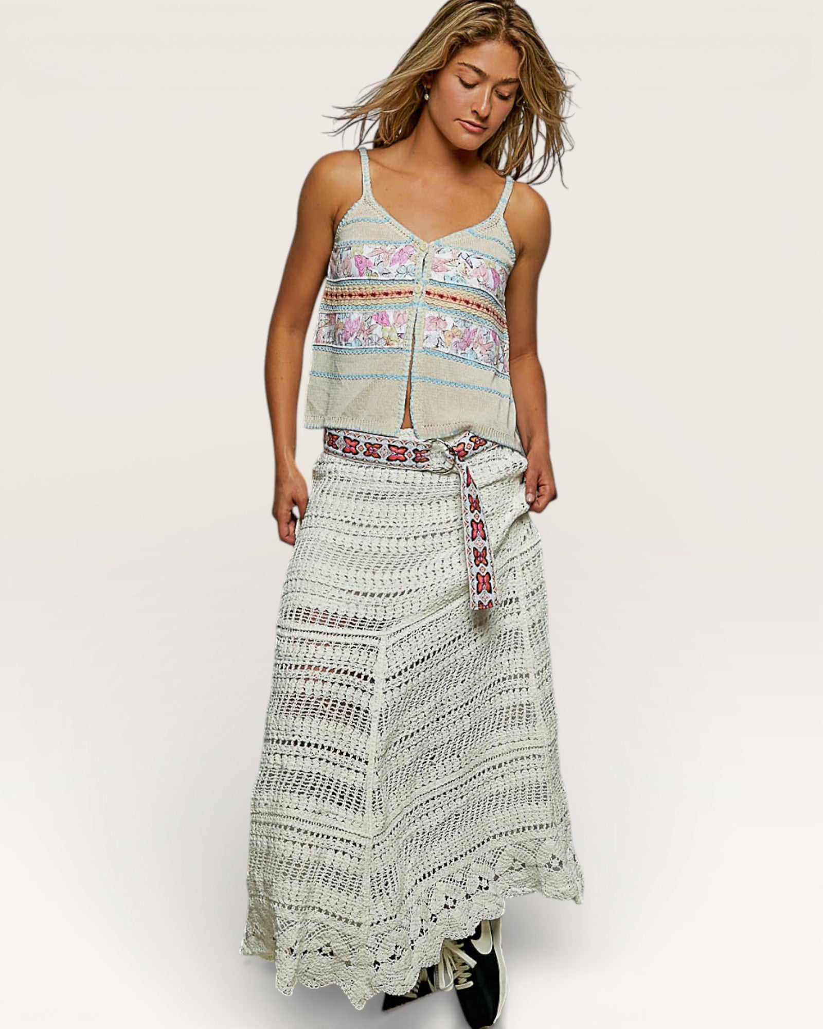 Woman wearing a patterned top and long skirt on a white background