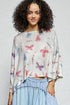 Woman wearing a butterfly-patterned top with a plain background